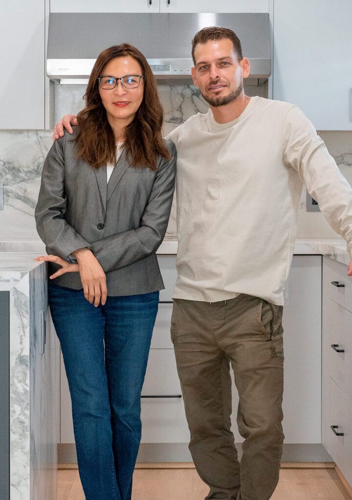 The owners smiling while standing in kitchen