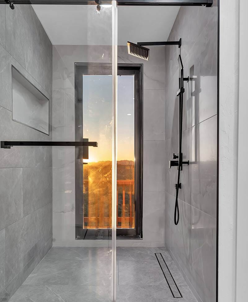 Grey-walled shower with a glass door leading outside to balcony